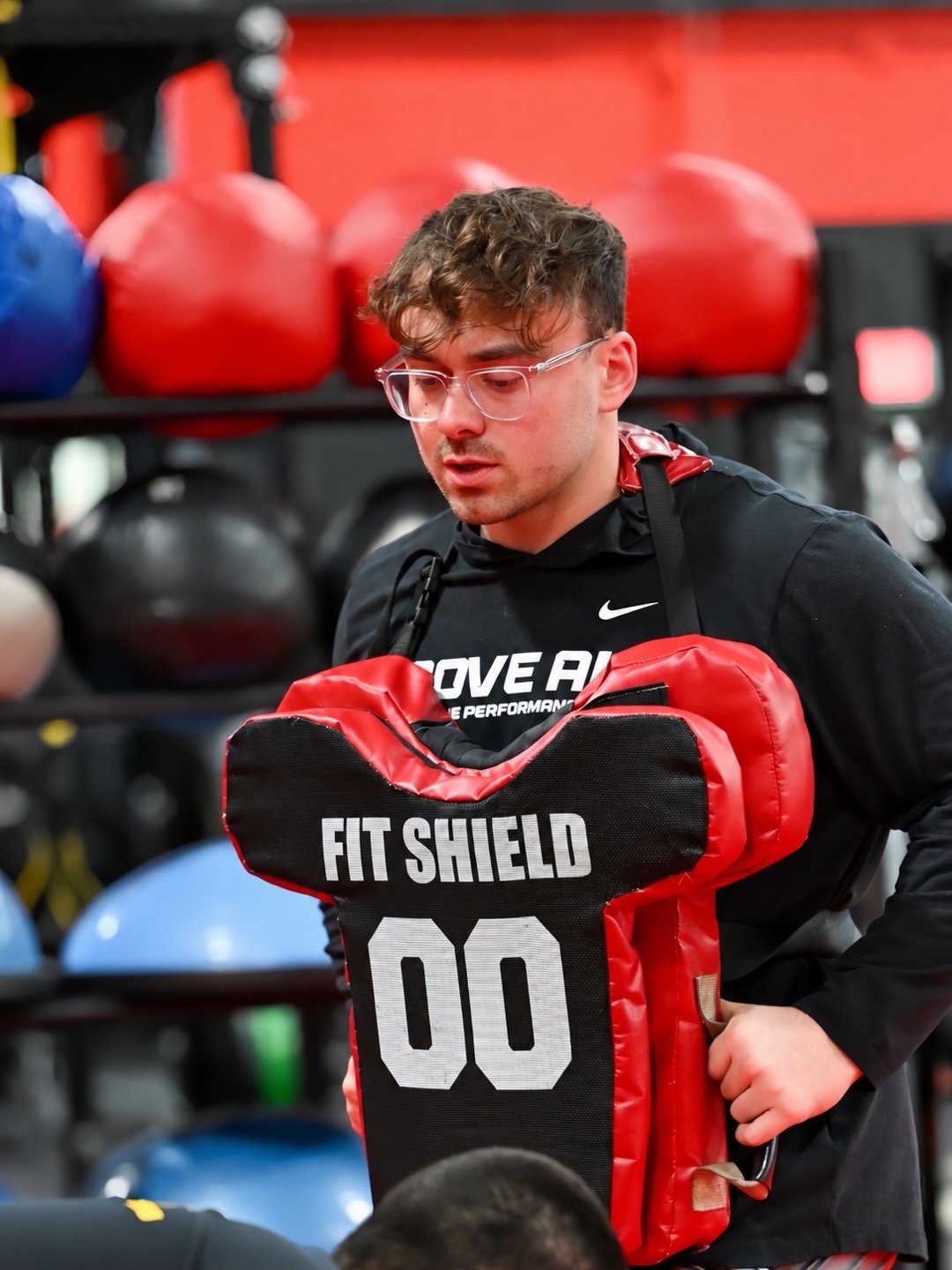 Coach Buj holding a Fit Shield blocking pad in the gym